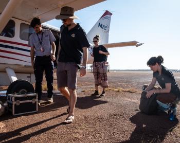 Pilot and healthcare workers with plane on apron.