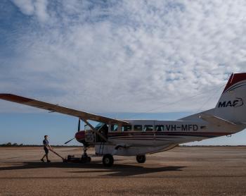 Maintenance engineer wheeling aircraft out of hangar.
