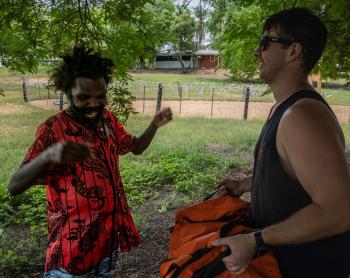 two men laughing in the shade of a tree