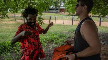 two men laughing in the shade of a tree