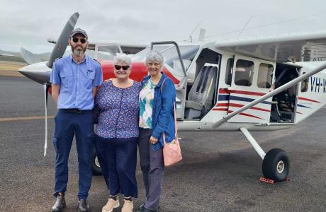 Pilot and passengers standing on tarmac in fron of GA8 aircraft