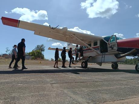 Passengers walking out to aircraft accompanied by pilot
