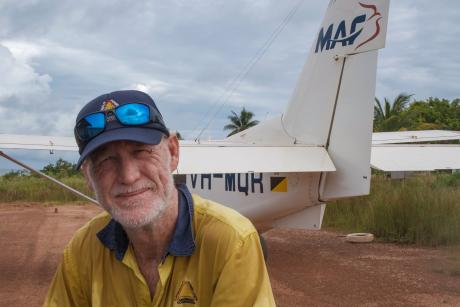 workman looking into camera with aircraft in background