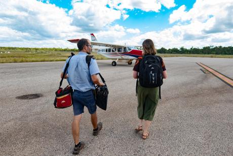 Pilot and woman walking out to aircraft on airstrip