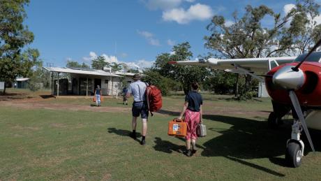 People carrying fraight from aircraft across lawn
