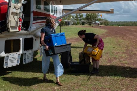 People unloading plasctic tubs from aircraft